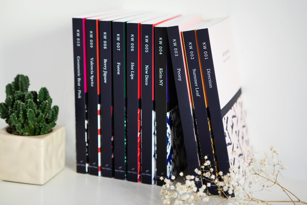 The full Kate Whyley journals range on a bookshelf, styled with a cactus plant and white flowers
