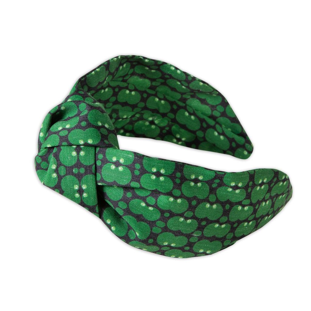 A Kate Whyley wide, knotted headband with a green and dark grey circle pattern, called Forest