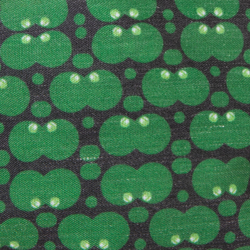 A close up image of Kate Whyley wide, knotted headband cotton fabric, with a green and dark grey circle pattern, called Forest