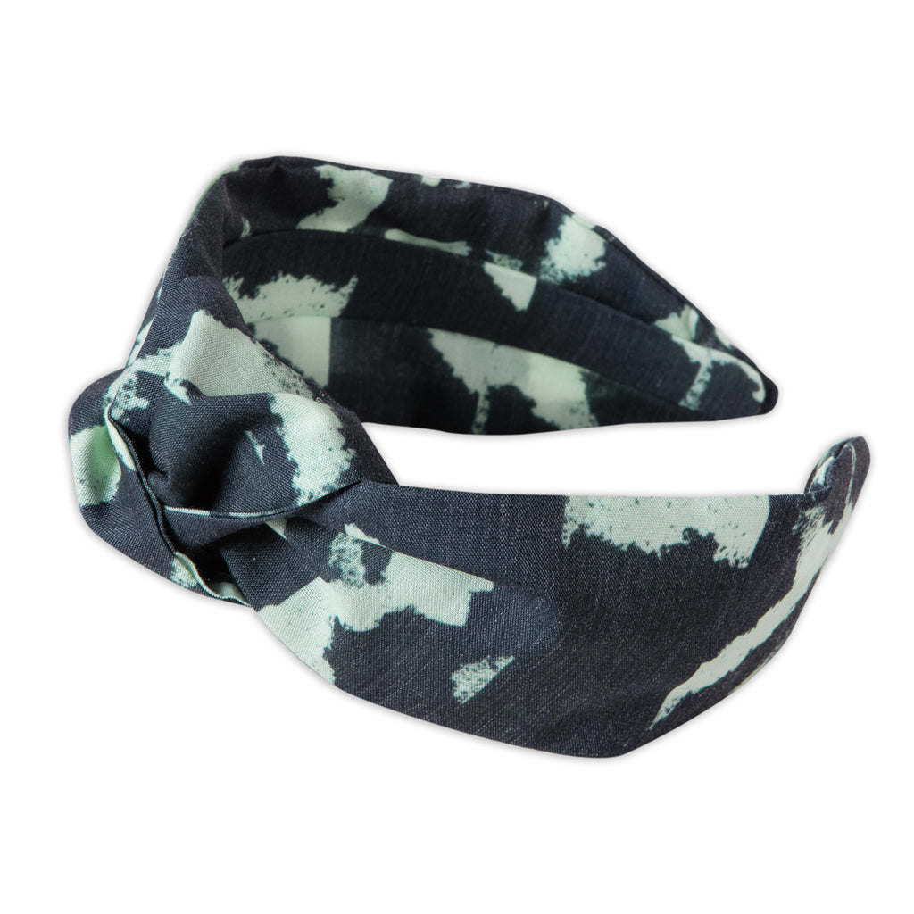 A Kate Whyley wide, knotted headband with a mint green and navy pattern, called Studio