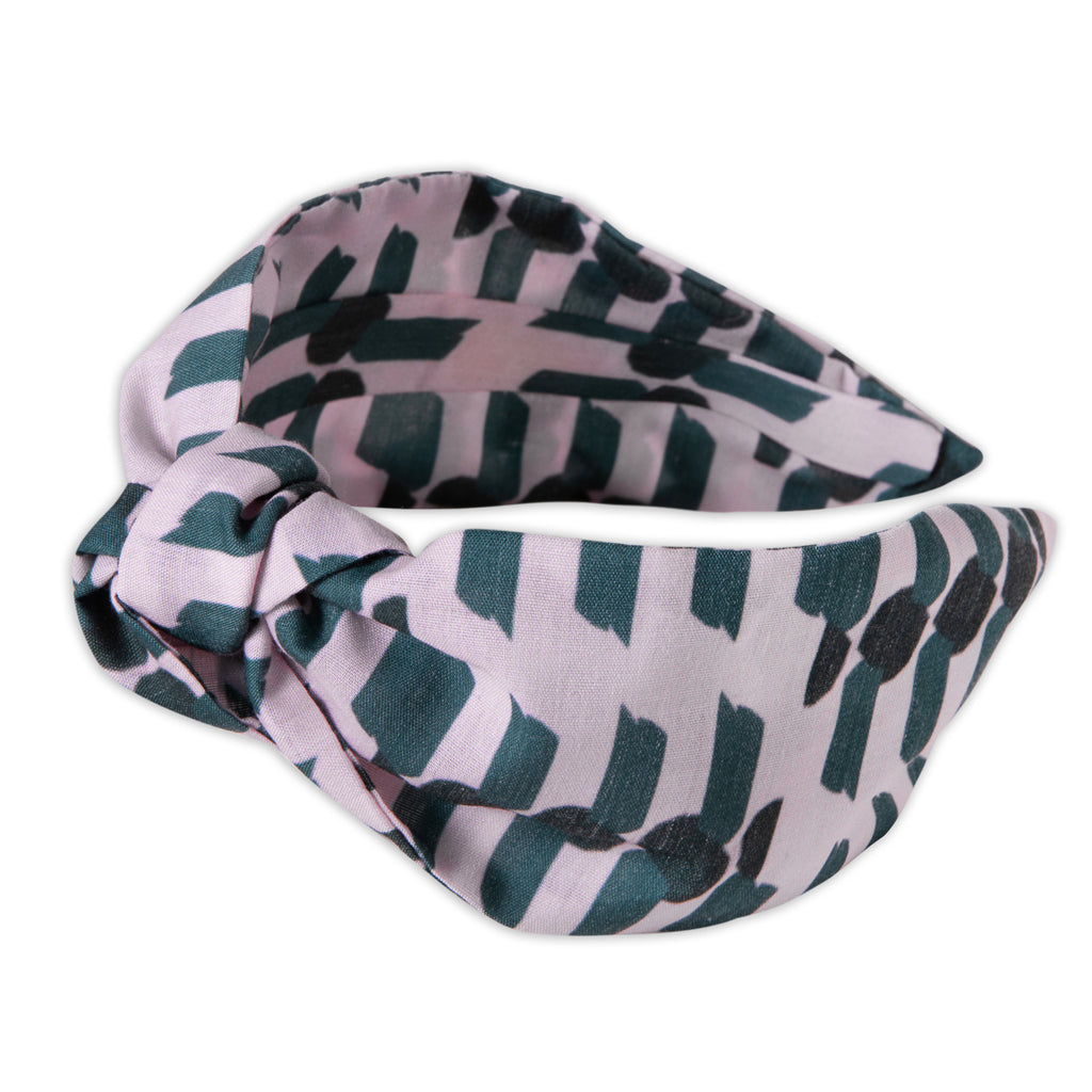A Kate Whyley wide, knotted headband with a bottle green and blush pink pattern, called Peony