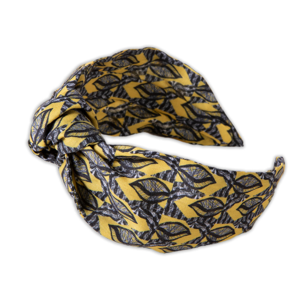 A Kate Whyley wide, knotted headband with a yellow, grey and black pattern, called Summer Leaf