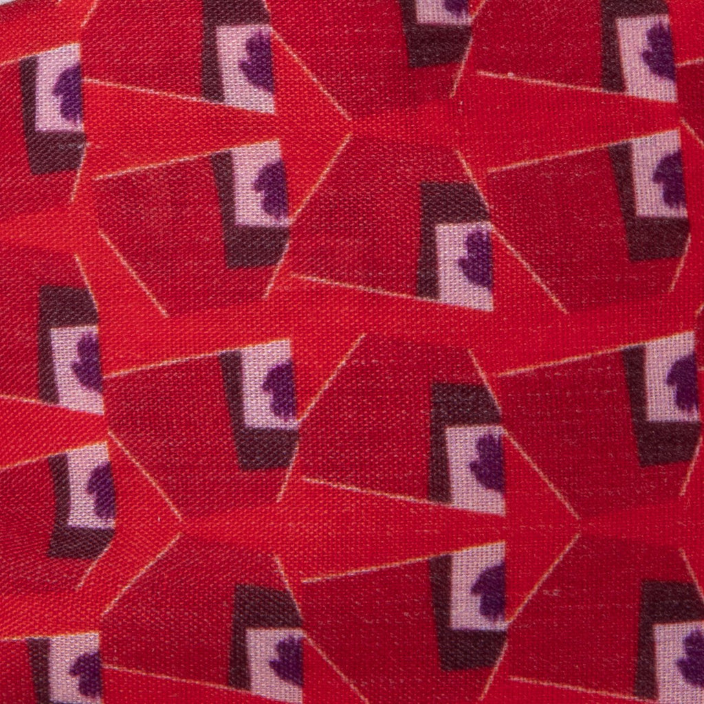 A close up image of Kate Whyley wide, knotted headband cotton fabric, with a red, burgundy and white pattern, called Hot Lips