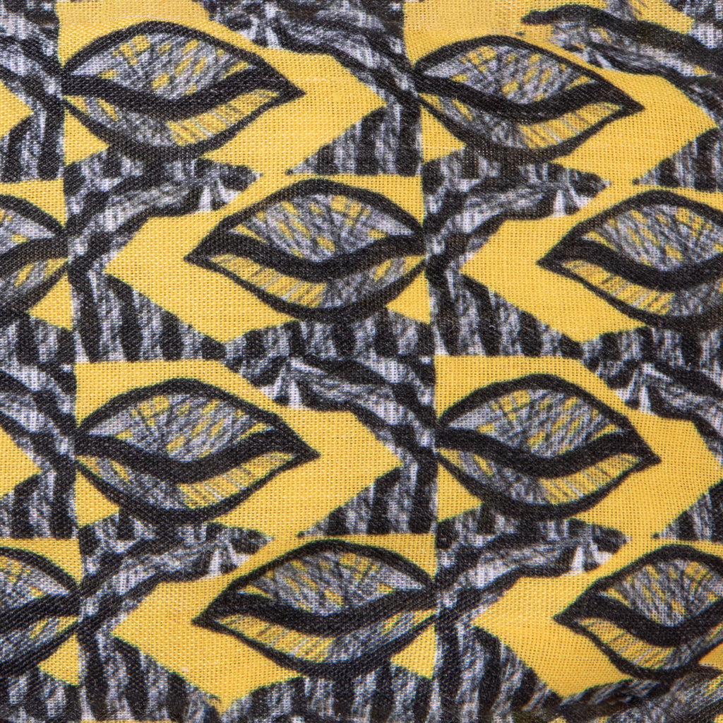 A close up image of Kate Whyley wide, knotted headband cotton fabric, with a yellow, grey and black pattern, called Summer Leaf