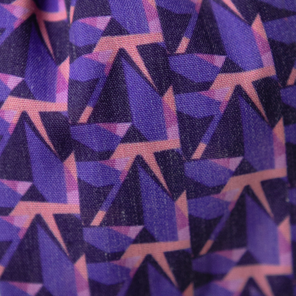 A close up image of Kate Whyley wide, knotted headband cotton fabric, with a purple and pink pattern, called Nitesky