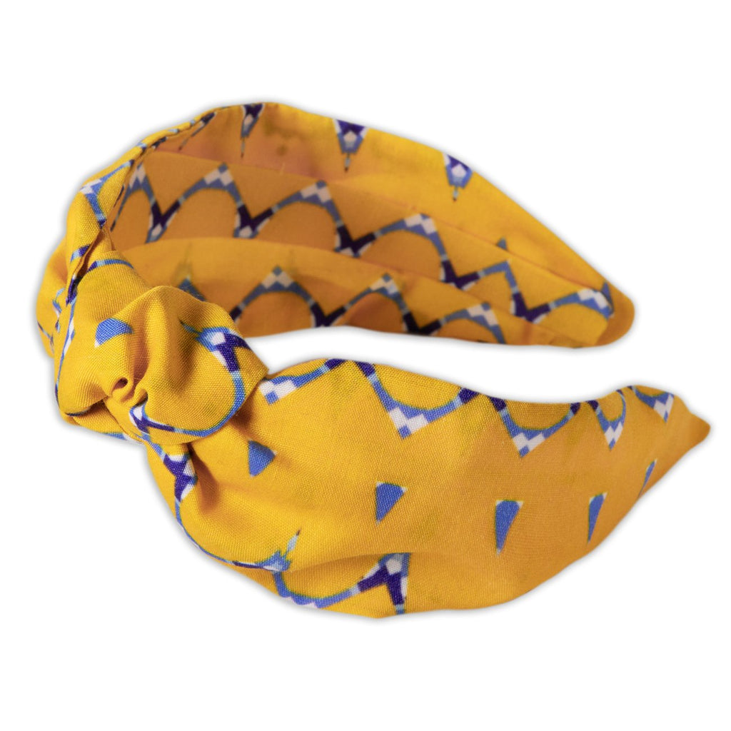 A Kate Whyley wide, knotted headband with a yellow, blue and white and pattern, called Holding Hands